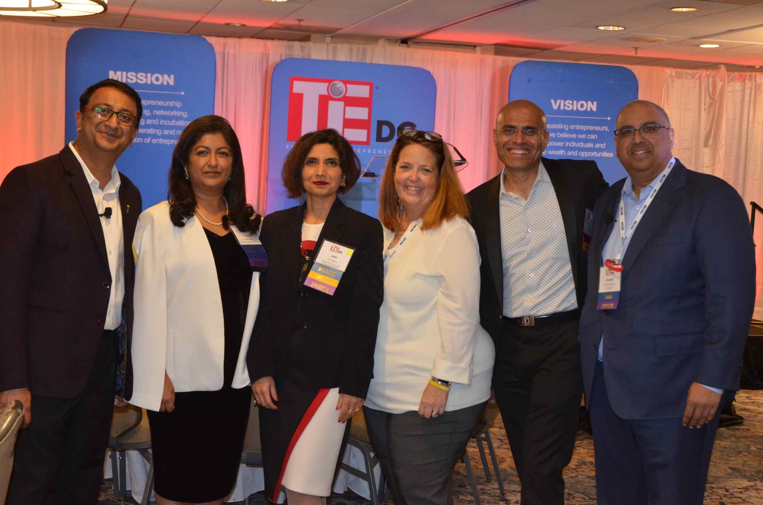 Members of TiE DC at an event, with their mission and vision displayed at the background.